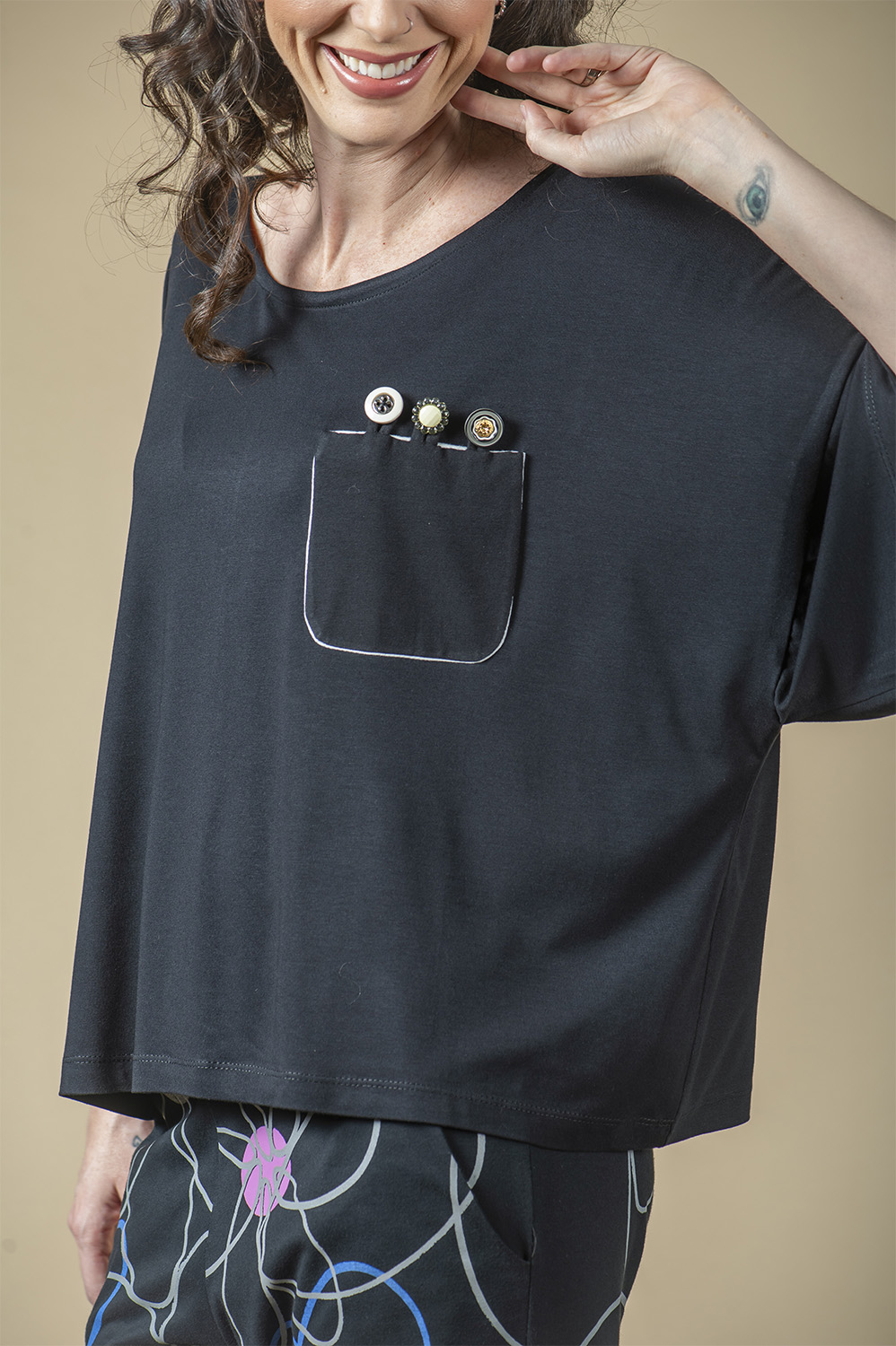 BLUSA QUADRADA TIPO T-SHIRT COM AMARRAÇÃO DE BOTÃO NO PESCOÇO E CUSTOMIZAÇÃO DE BOLSO NA FRENTE COM DETALHE DE 3 BOTÕES