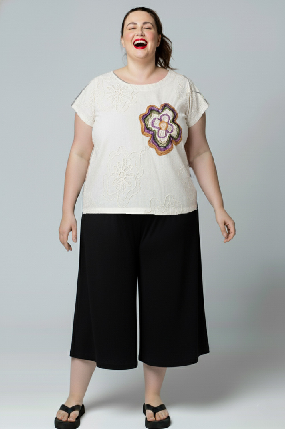 BLUSA PLUS SIZE RETA COM MANGA CURTA, DECOTE REDONDO, PENCES NO BUSTO CUSTOMIZADA COM APLICAÇÕES MANUAIS DE BORDADO NAS FLORES